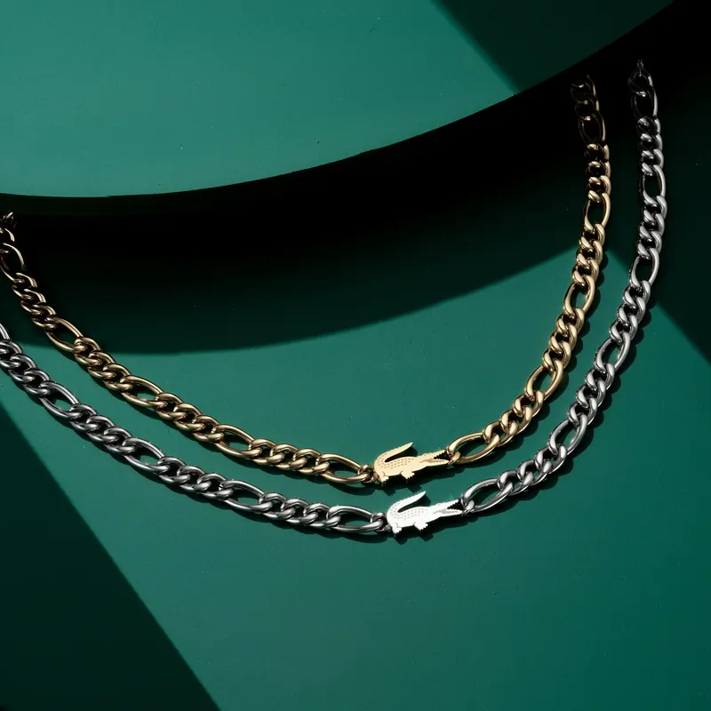 Gold and silver figaro chains with crocodile clasps on curved green surfaces.