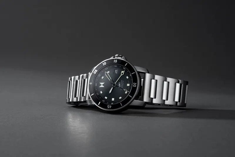 Steel MVMT dive-style watch with a black dial on a dark grey graduated background.