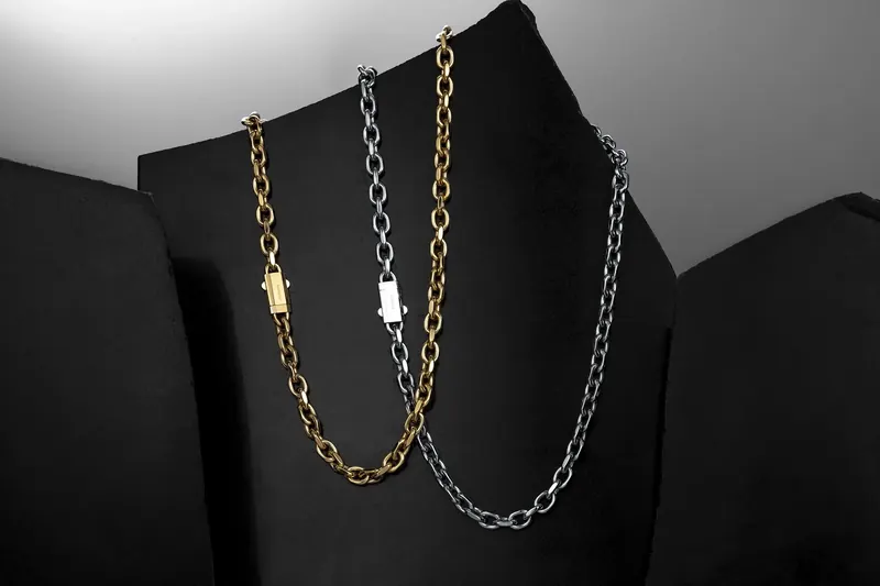 Gold and silver chain necklaces hanging against folded black material.