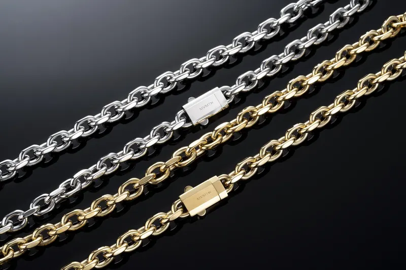 Close-up of silver and gold link chain bracelets under hard light on a black background.
