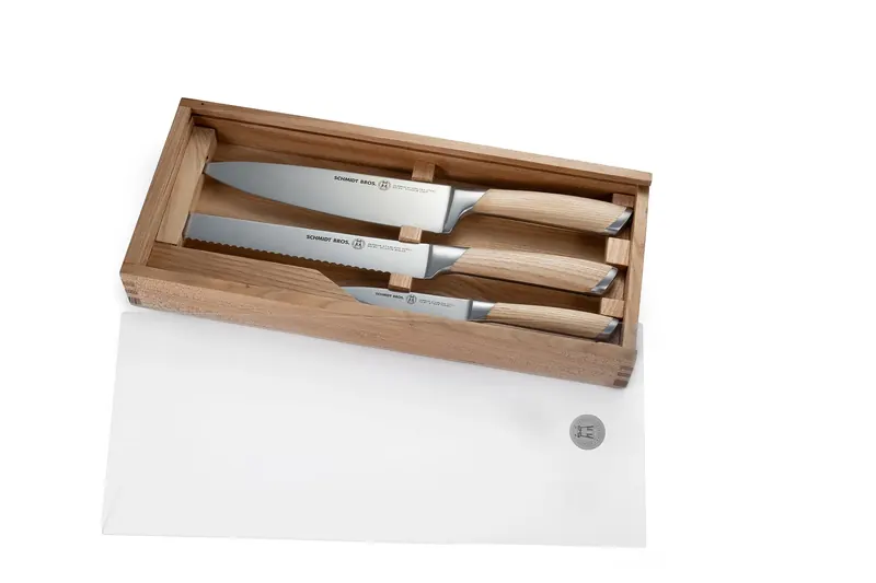 Three Schmidt Bros. kitchen knives with wooden handles in an open wooden gift box on white.