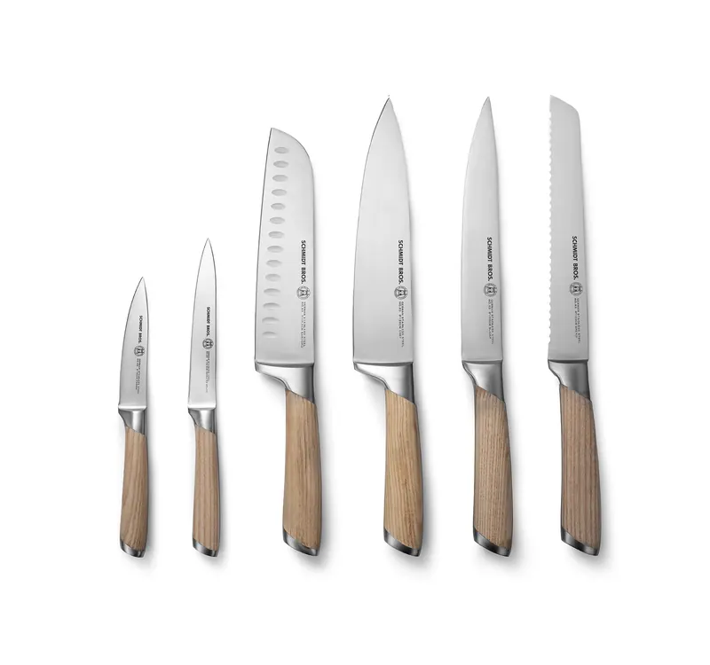 Six steel kitchen knives with walnut handles standing upright in a row from smallest to largest on white.