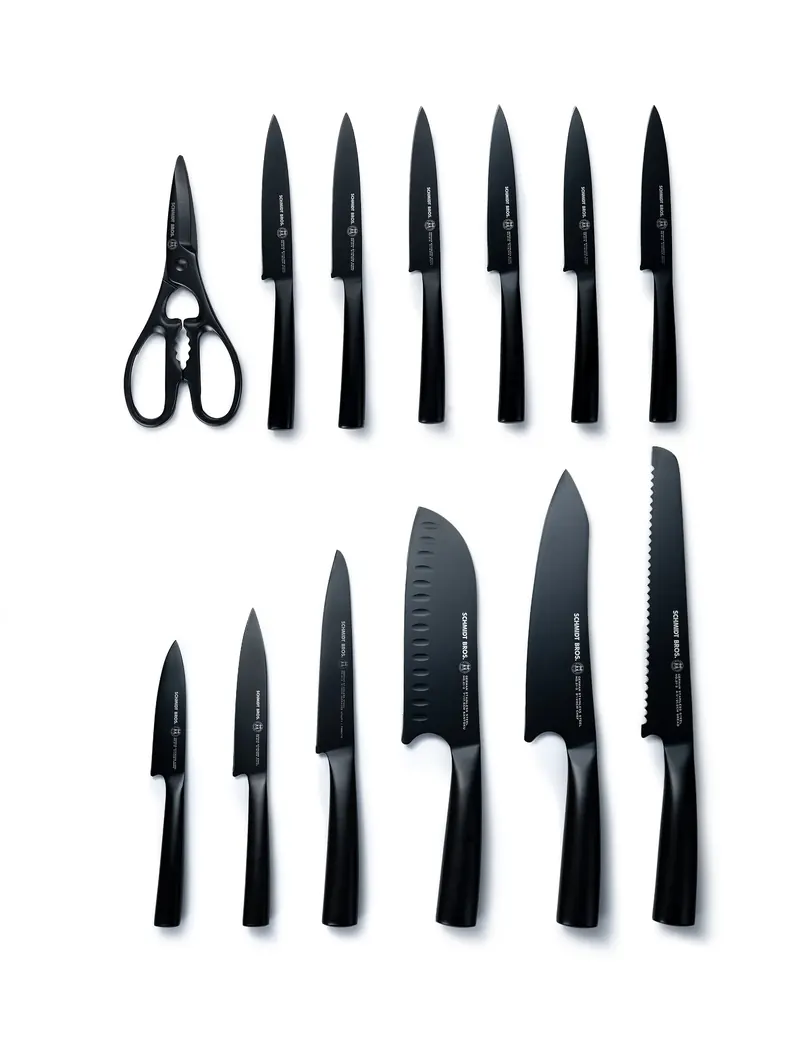 Black kitchen knife set with shears laid flat in two rows on a white background.