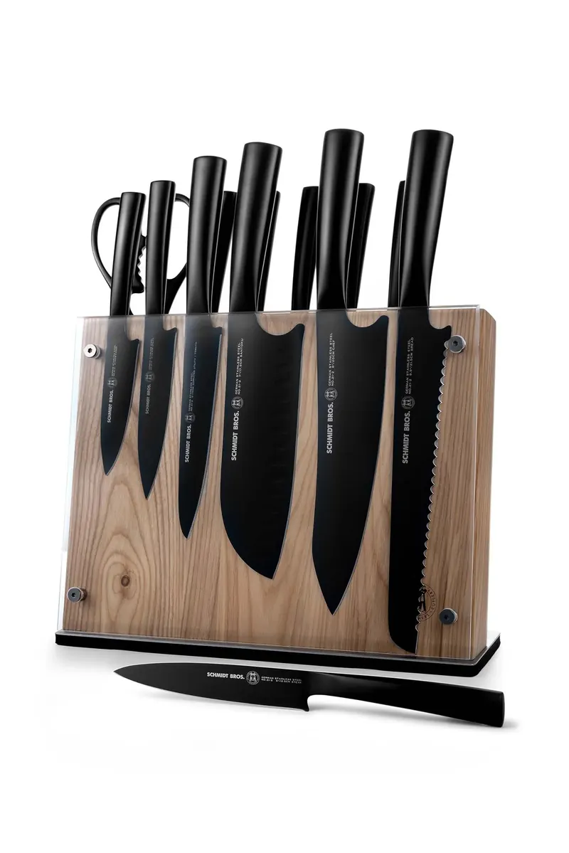 Six black kitchen knives and a honing steel in a wooden and clear acrylic block, with the steel lying in front.