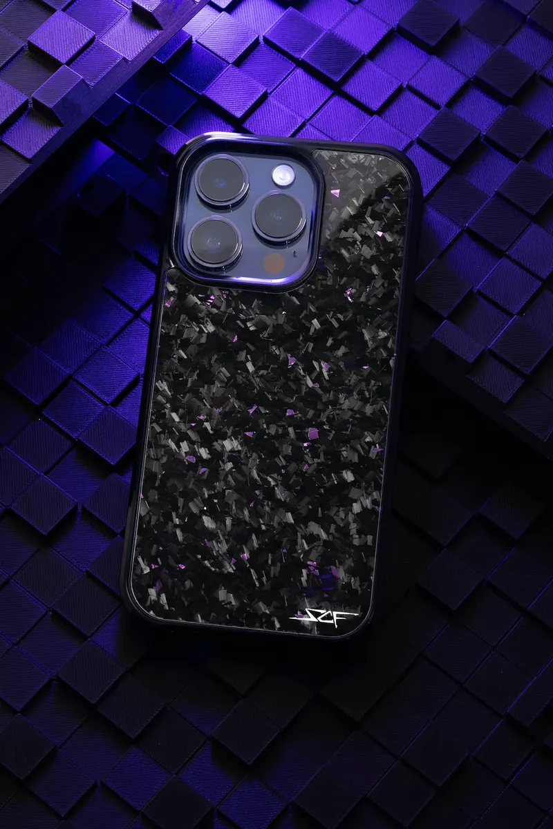 Phone in a black forged-carbon case on a field of cubes lit purple and blue.