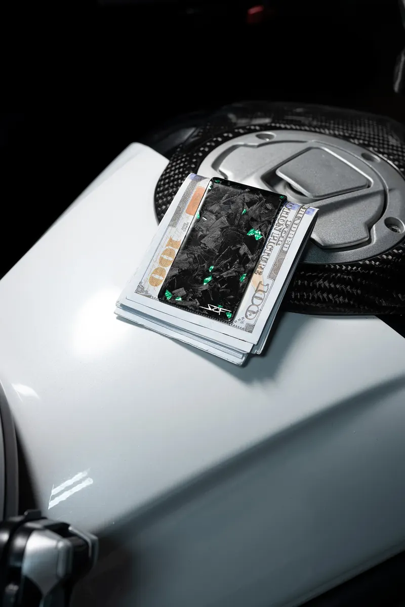 Marbled forged-carbon card holder with cards on the white fuel tank of a motorcycle.