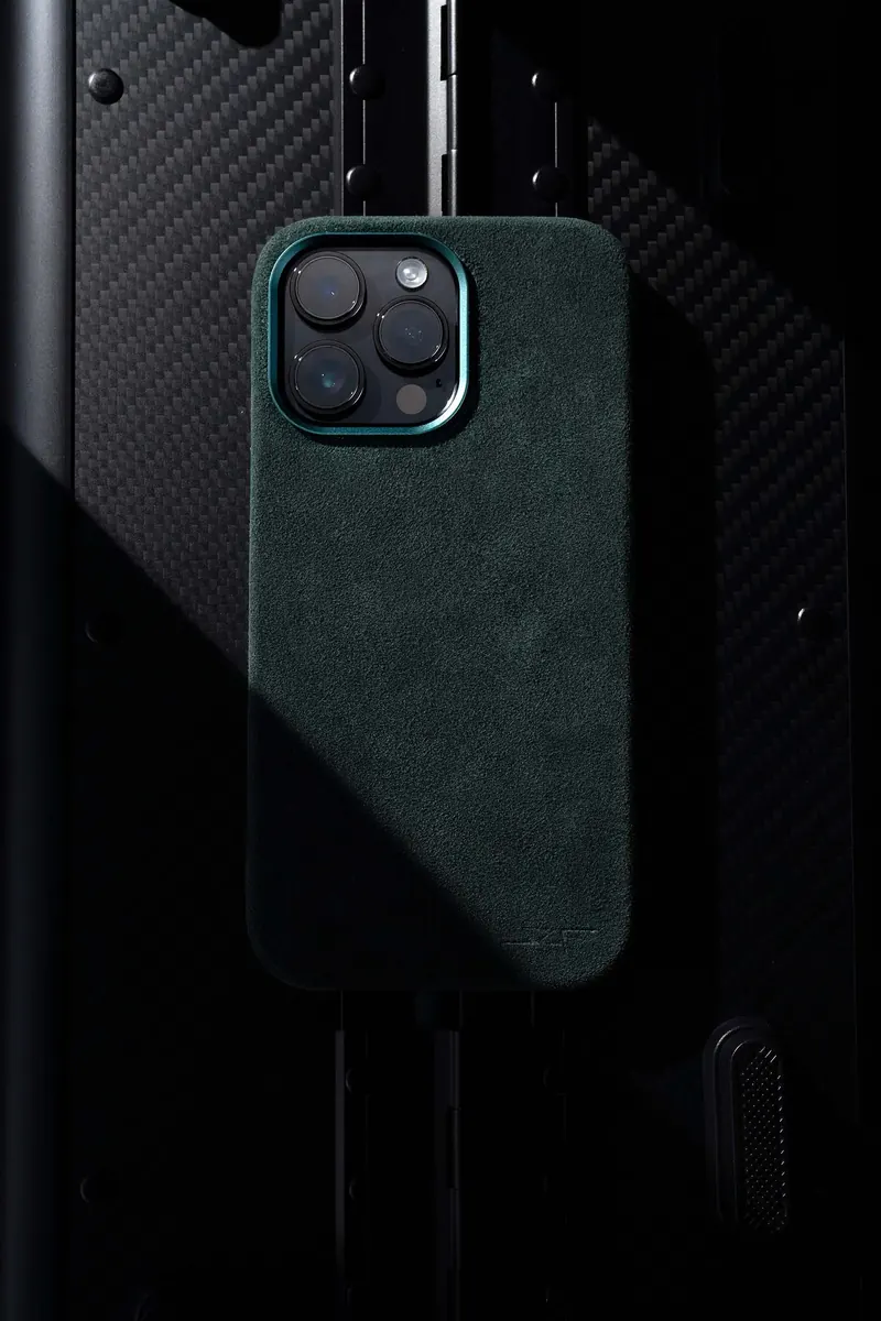 Green smartphone with a textured back and three camera lenses, on a black textured surface.