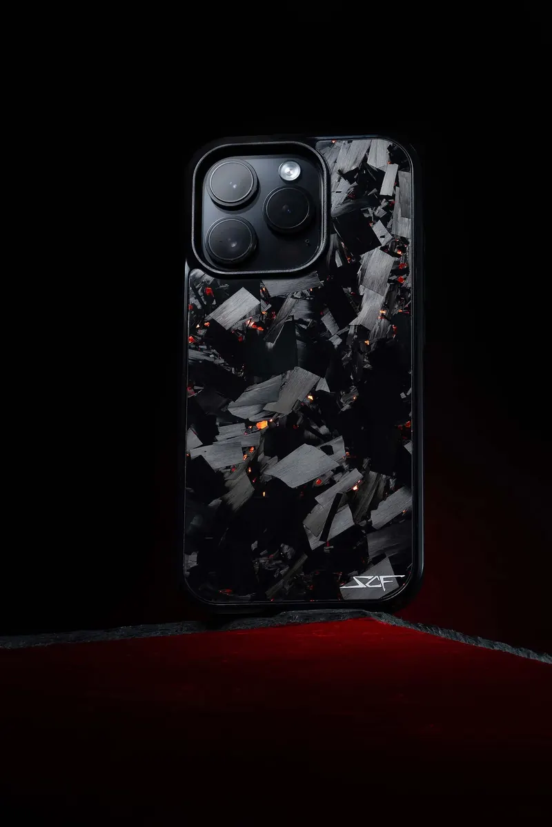 Smartphone with a cracked, shattered-look back showing black and metallic fragments against a dark background.