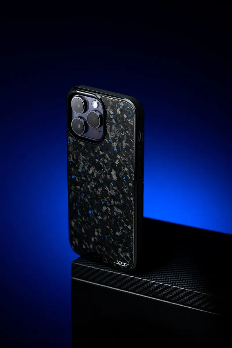 Phone in a flecked forged-carbon case on a black block with a blue edge light.