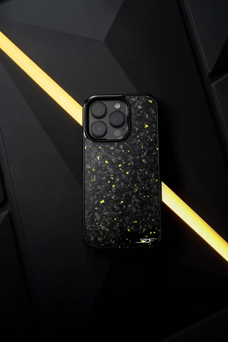 Phone in a black and gold-flecked case beside a diagonal yellow light strip.