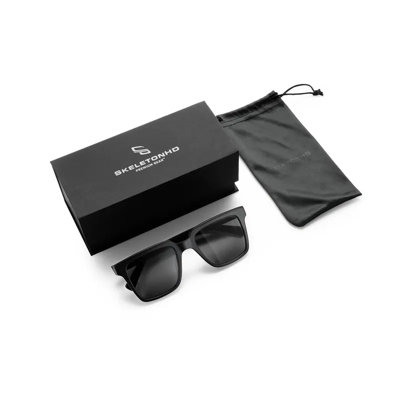 Black sunglasses in front of a Skeleton HD box and grey cloth pouch on white.
