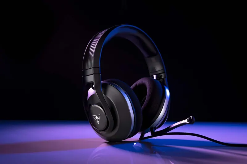 Black gaming headset with a microphone, lit by purple and blue LED light on a reflective black surface.