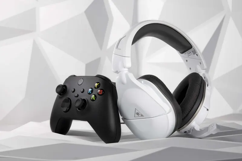 Black Xbox controller and white gaming headset resting on a white geometric surface.
