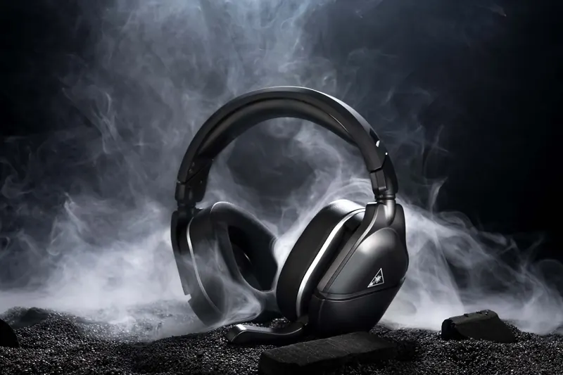 Black gaming headset with a microphone surrounded by smoke and dark rocks against a dark background.
