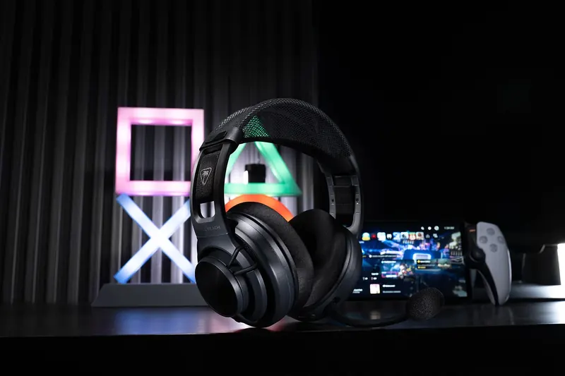 Black headset with a colorful earcup in front of a glowing sign and a handheld console.